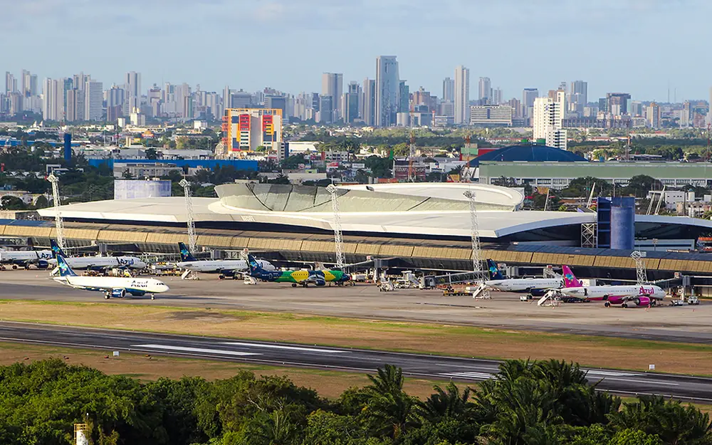 Aeroporto Internacional do Recife visto de longe, com o terminal em primeiro plano e os prédios da cidade ao fundo