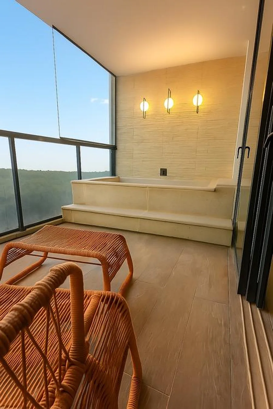 Banheira instalada na varanda do apartamento, com poltronas de fibra e vista aberta