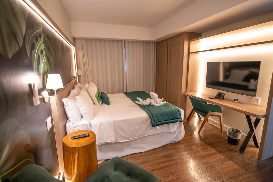 Suíte ampla com cama de casal, poltrona de leitura e área de estar