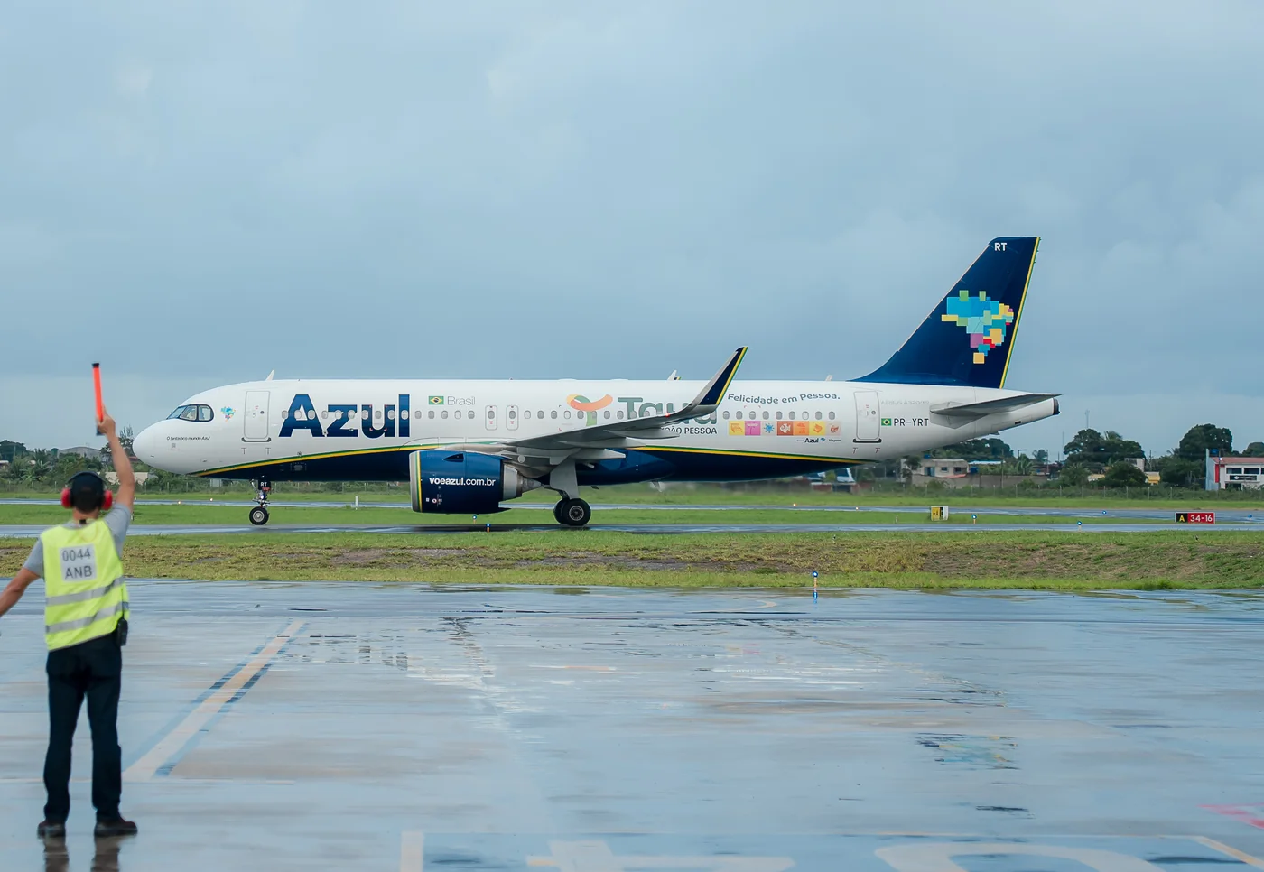 Aeronave da Azul com a marca do Tauá Resort João Pessoa na fuselagem, taxiando na pista enquanto um agente de pátio sinaliza