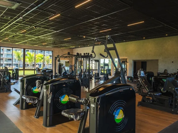 Academia do resort com esteiras, aparelhos de musculação e vista para o jardim