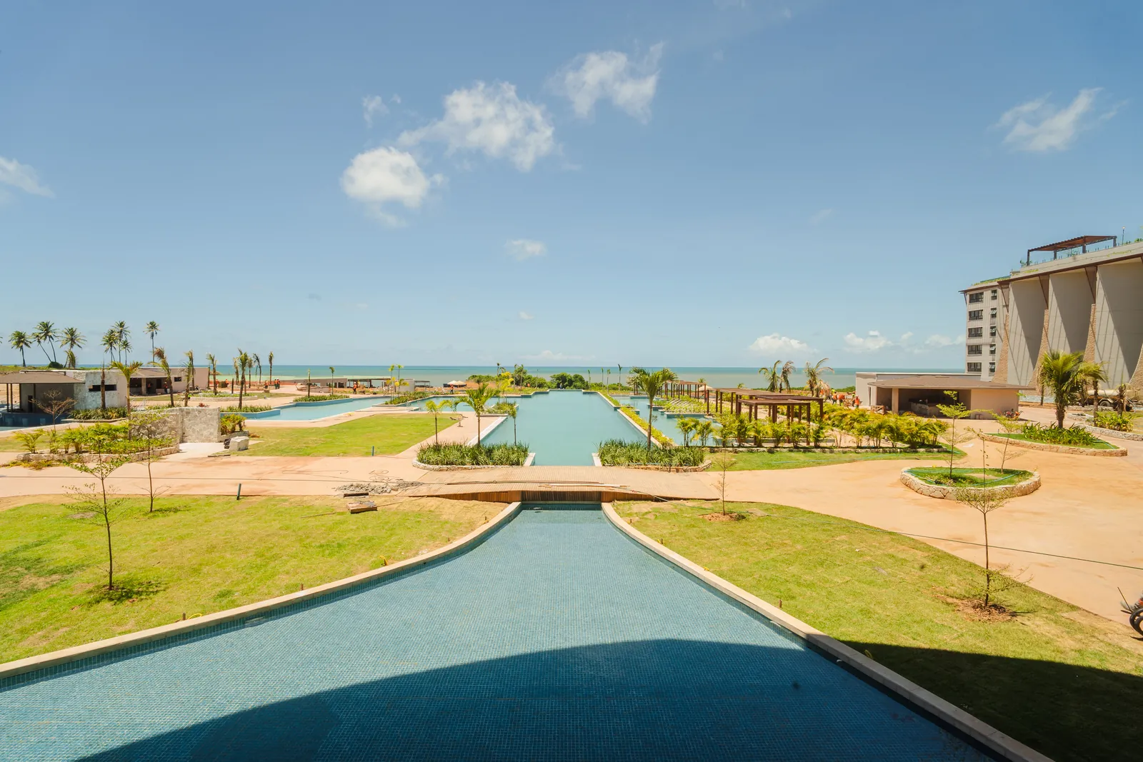 Vista ampla do Tauá Resort João Pessoa, com os jardins, o rio lento e o mar ao fundo