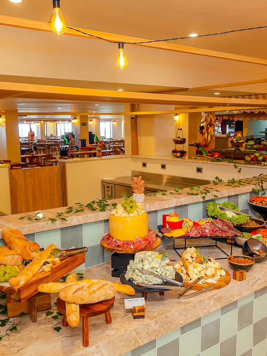 Ilha do buffet da Casa Nordestina, com pães, saladas e pimentas decorativas penduradas