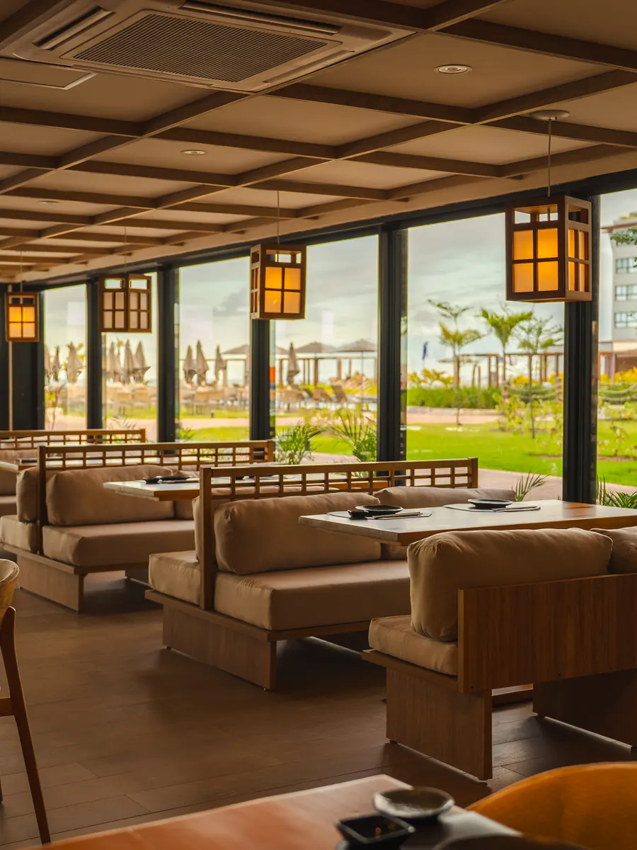 Salão do restaurante japonês Nigori, com luminárias de papel, mesas baixas e vista para o jardim