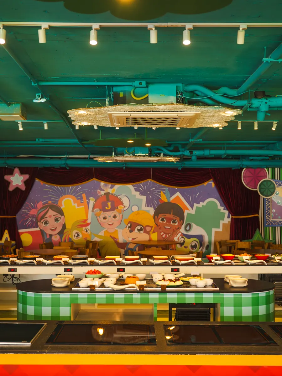 Buffet do Restaualegres, o restaurante infantil, com balcão na altura das crianças e o painel dos personagens Taualegres ao fundo
