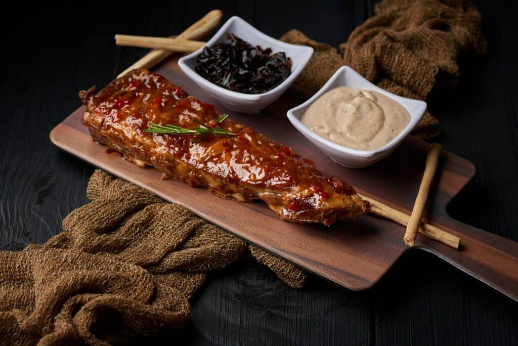 Costela assada acompanhada de maionese e barbecue.