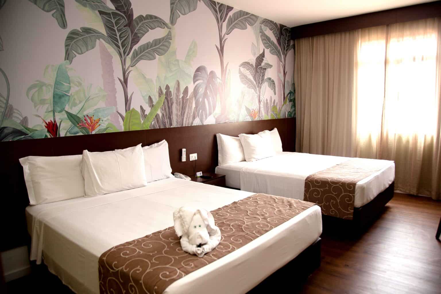 Apartamento quadroplo com decorado com pintura de folhagem e cama feita com cocha marrom.