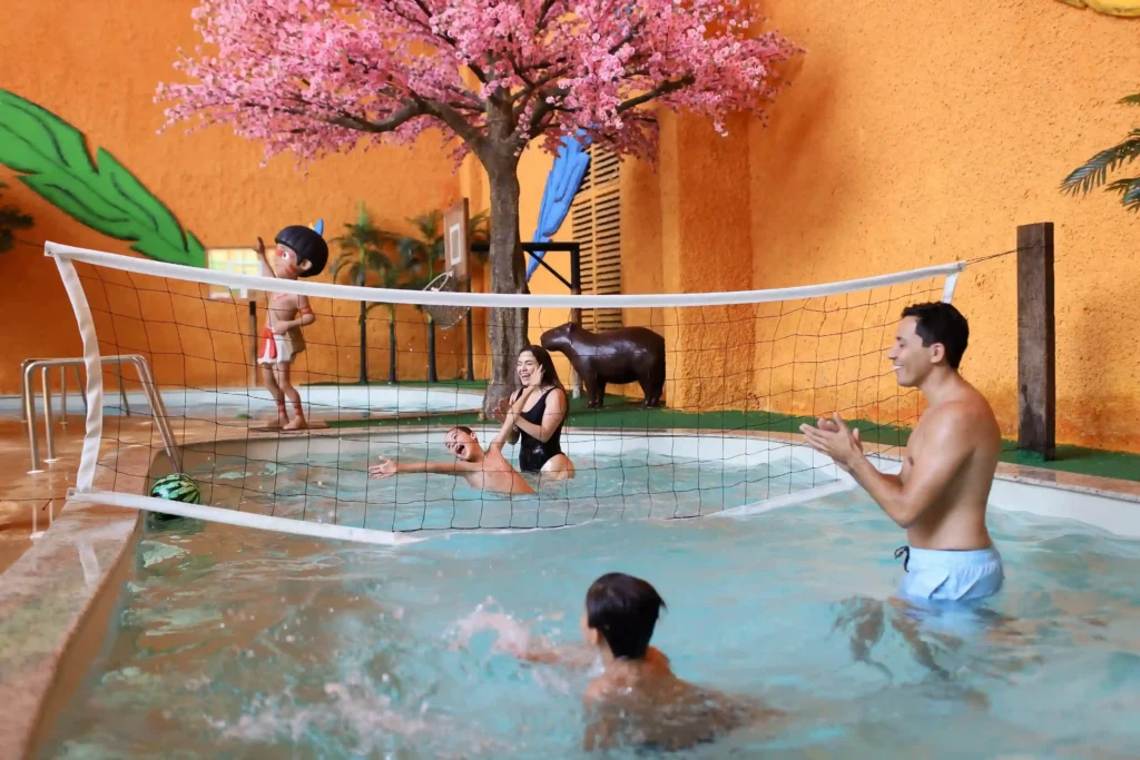 Família brincando na quadra de vôlei aquático em um espaço temátizado do Torí. 