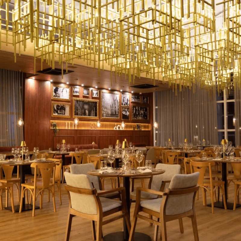 restaurante italiano exclusivo do Tauá ornamentado com luminárias contemporâneas douradas, espaço amplo com bar.