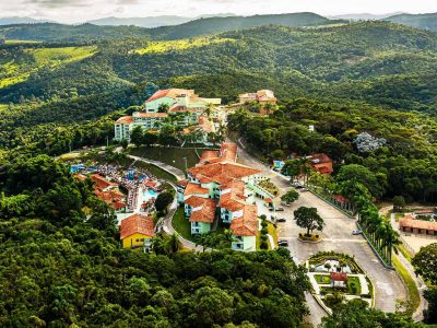 Vista aérea do Tauá Resort Caeté, com árvores e uma serra bem verde ao redor.