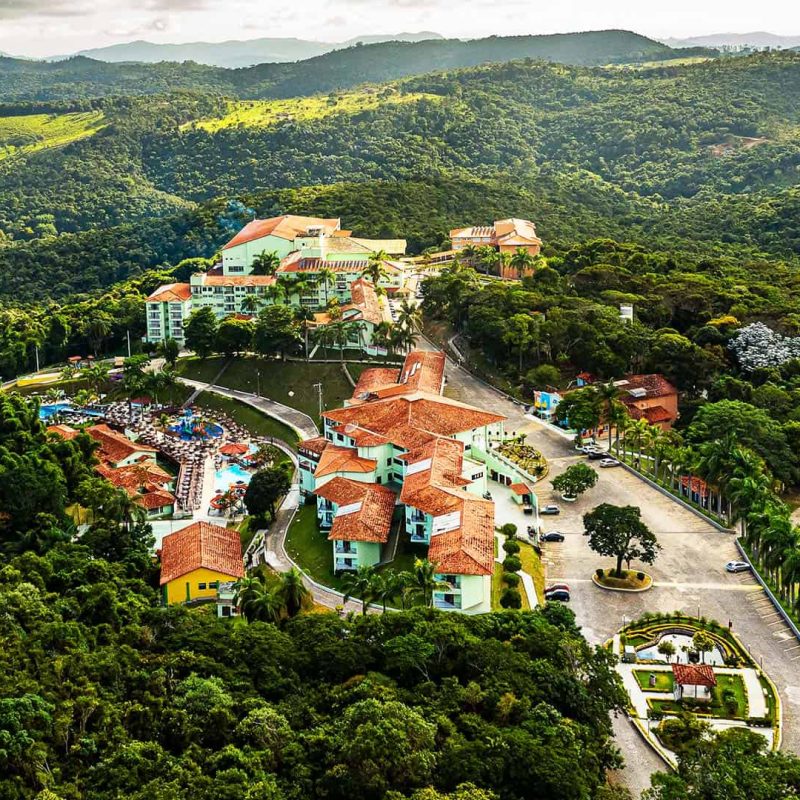 Vista aérea do Tauá Resort Caeté, com árvores e uma serra bem verde ao redor.