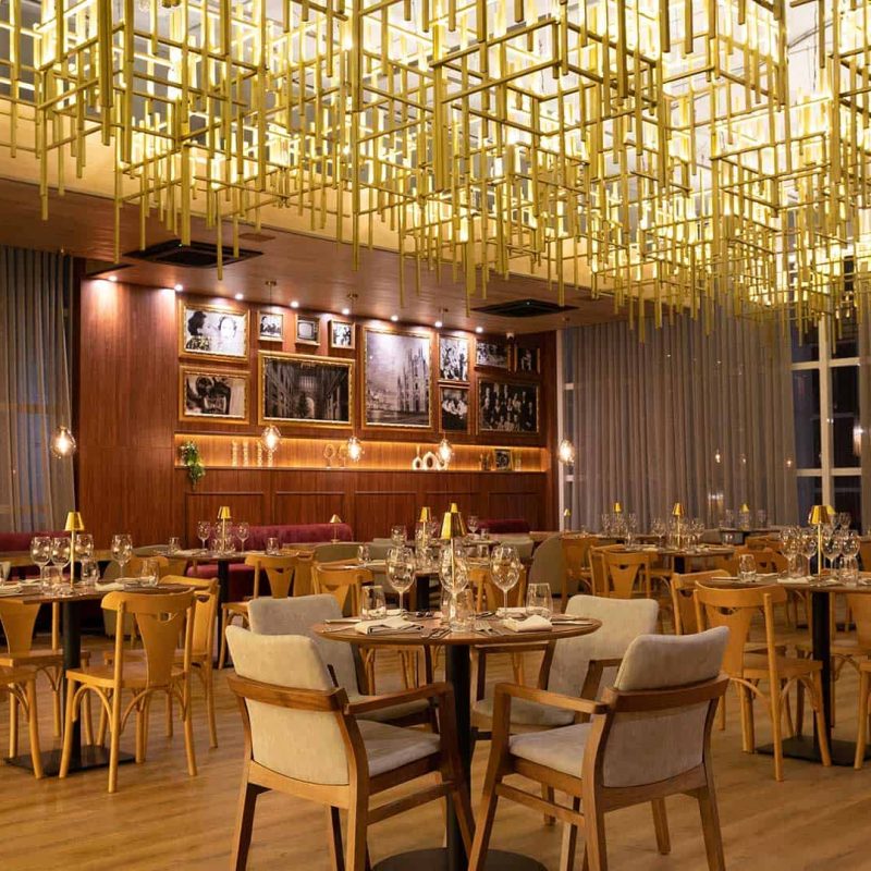 restaurante italiano exclusivo do Tauá ornamentado com luminárias contemporâneas douradas, espaço amplo com bar.